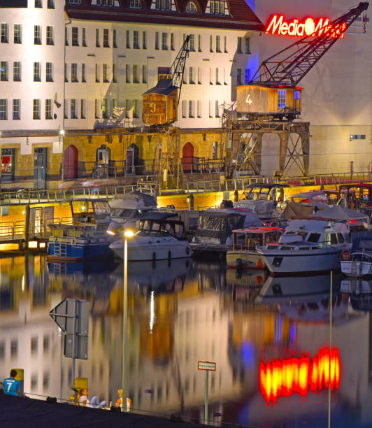 nacht erschossen von einem beleuchteten hafen am teltow-kanal in berlin-tempelhof mit booten, alten lagerhallen, kränen und reflexionen auf dem wasser. - teltow stock-fotos und bilder