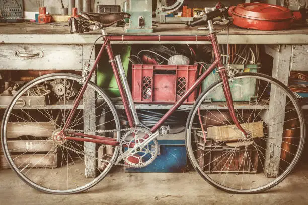 Photo of Vintage racing bycicle in front of an old work bench with tools