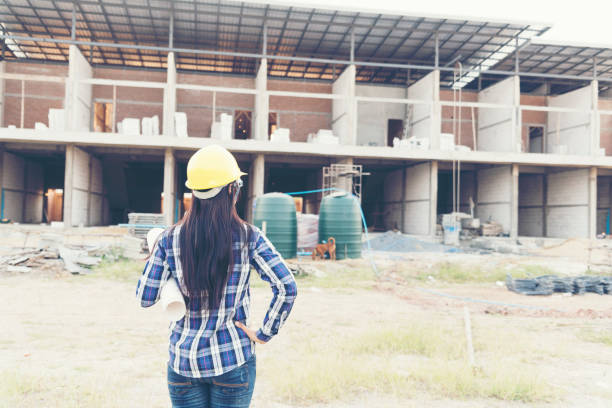 istock Woman engineering working on construction site and holding yellow hard hat safety helmet. Construction Concept. 1010590010