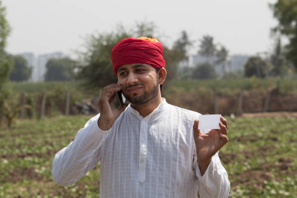 istock Farmer holding blank card and talking on mobile phone 1010590234