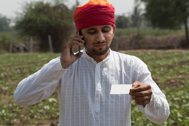 istock Farmer holding blank card and talking on mobile phone 1010590486