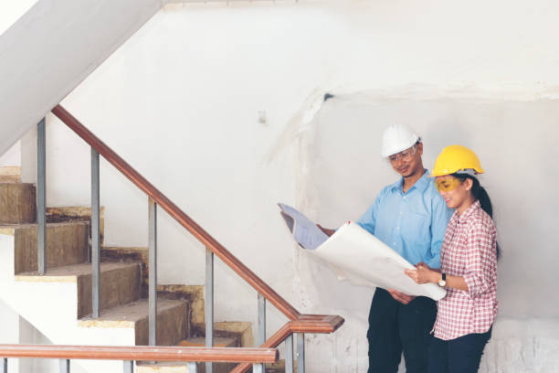 istock Success Engineer wear white helmet for safety and checking building plans blue print. construction Concept. 1010598608