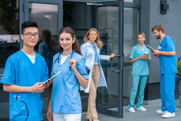 istock teacher opening doors, multicultural students standing on yard of medical university 1010598834