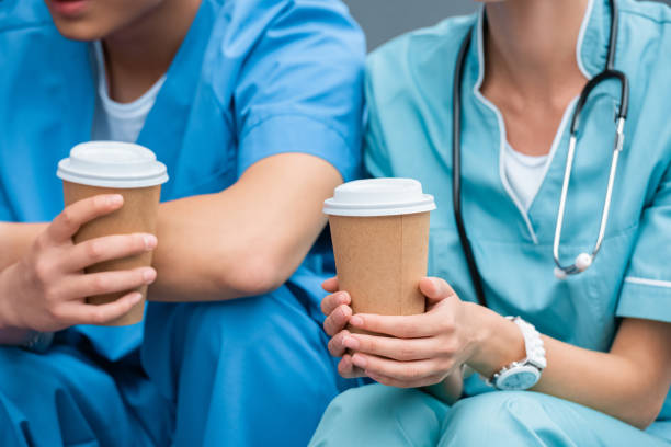 cropped image of medical students holding disposable coffee cups