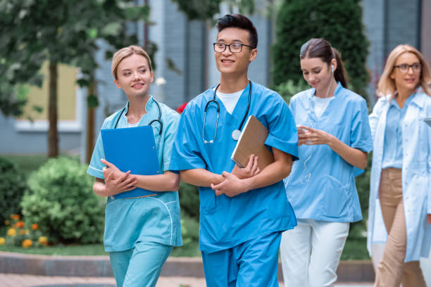 multicultural students and teacher walking on street near medical university multicultural students and teacher walking on street near medical university medical student stock pictures, royalty-free photos & images