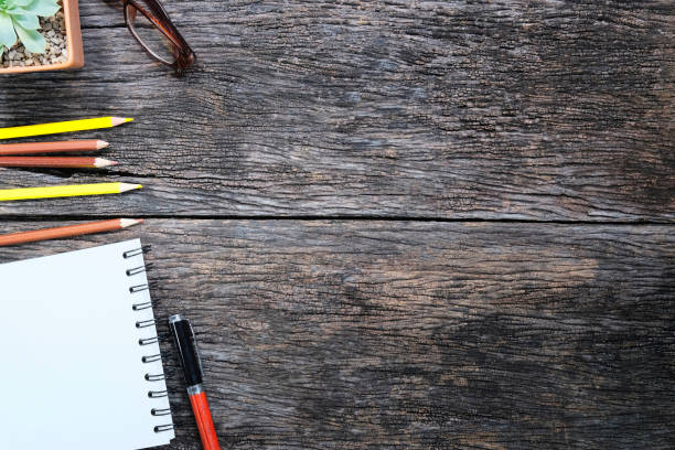 istock Copy space notebook paper and pen with colour pencil on wooden table. 1010602550