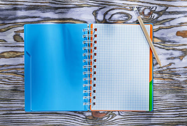 istock Checked spiral copybook pencil on wooden board 1010605178