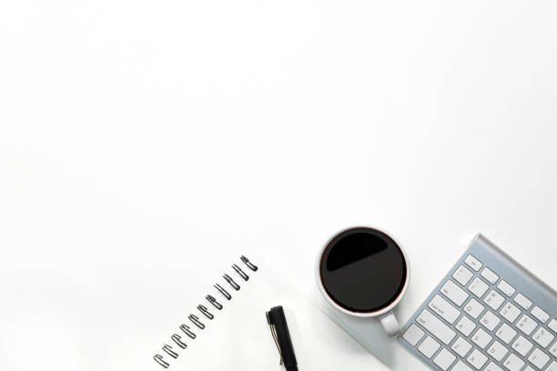 istock Modern white office desk table with keyboard computer, coffee, pen and notebook paper with workspace top view workspace. 1010605798
