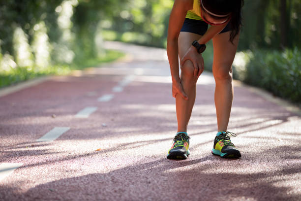 female runner suffering with pain on sports running knee injury - asian ethnicity jogging female women imagens e fotografias de stock