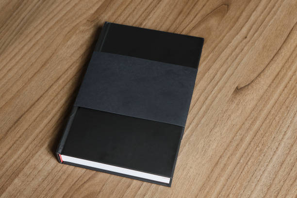 istock Black hardcover book with protector on wooden surface - mock-up black book 1010613786