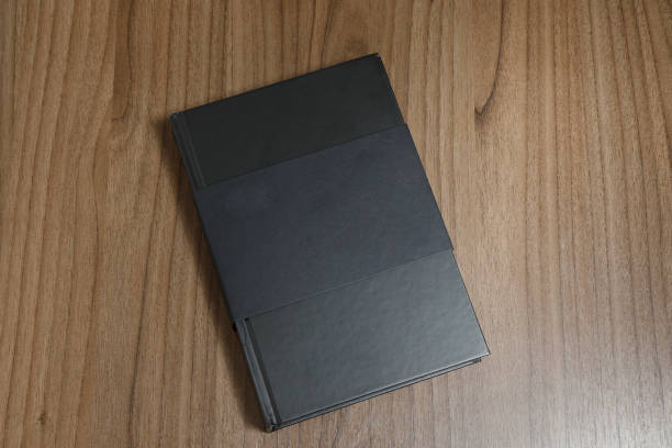 istock Black hardcover book with protector on wooden surface - mock-up black book 1010614034
