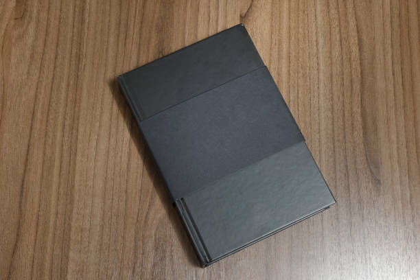 istock Black hardcover book with protector on wooden surface - mock-up black book 1010614338