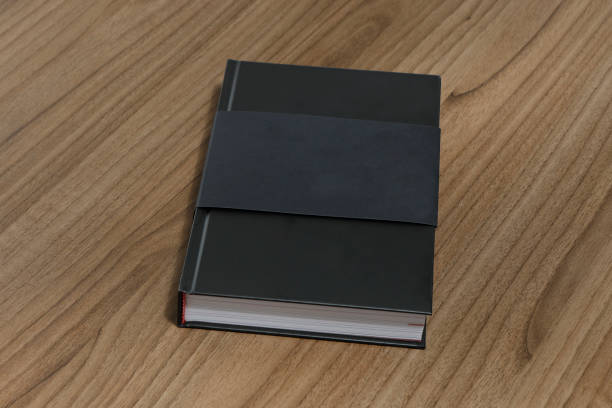 istock Black hardcover book with protector on wooden surface - mock-up black book 1010614502