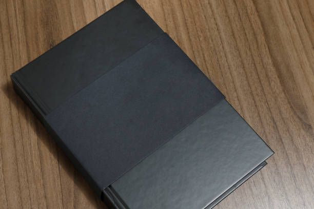 istock Black hardcover book with protector on wooden surface - mock-up black book 1010614648
