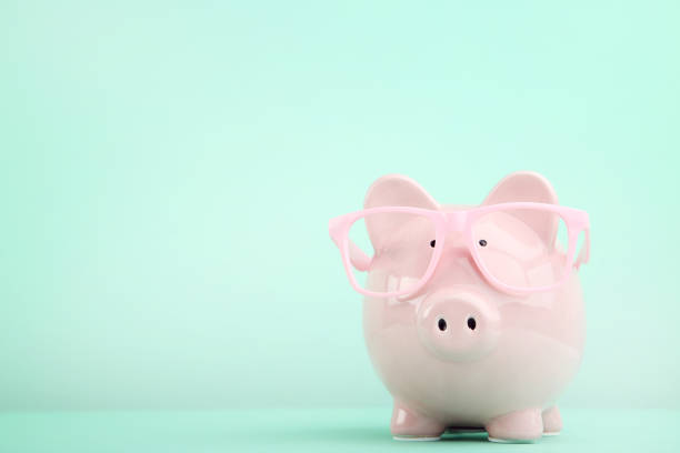 istock Pink piggy bank with glasses on mint background 1010618434