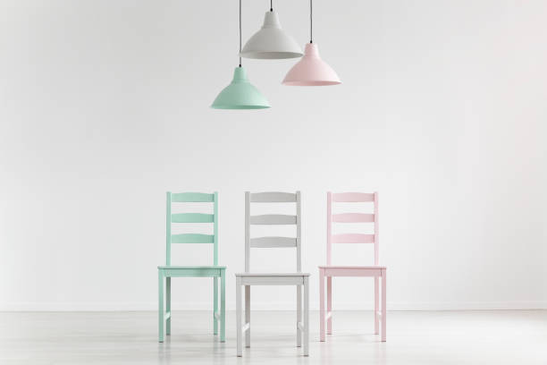 istock Lamps above chairs in mint, pink and grey color in white empty interior with copy space. Real photo 1010630048