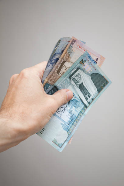 Hand holding Jordanian dinars banknotes Male hand holding Jordanian dinars banknotes over gray background, vertical photo dinar stock pictures, royalty-free photos & images