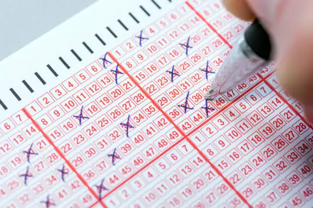 Photo of Completing a lottery ticket with a pen and hoping for quick riches