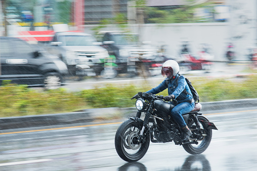 Nonthaburi, Thailand - July, 29, 2018 : Motion Blurred panning photo of Unidentified name people riding motorcycle in the rain on road at Nonthaburi, Thailand.