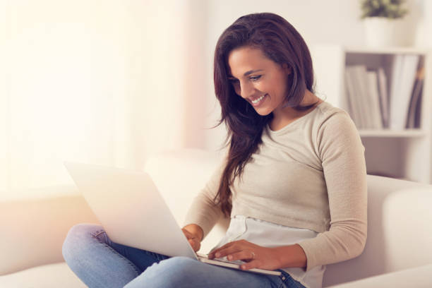 istock Happy Woman using a laptop on a couch 1010631212