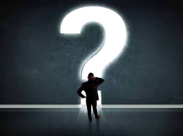 istock Business man looking at wall with a bright question mark 1010631858