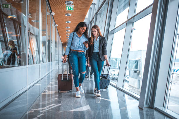 istock Female friends walking by window at airport 1010633980