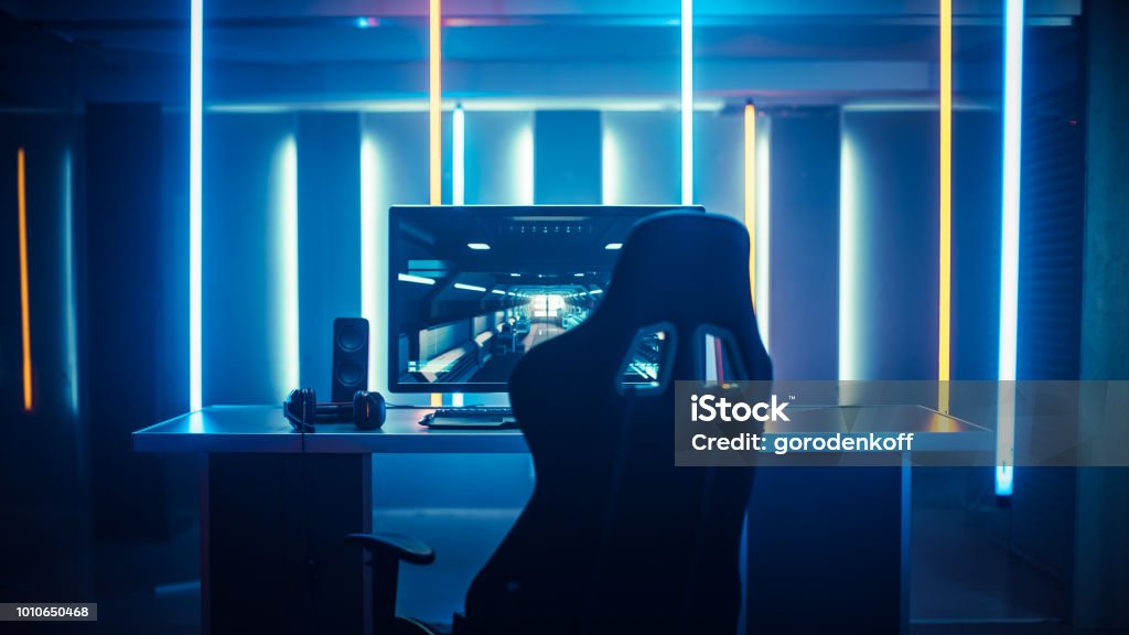 Professional Gamers Room With Ultra Powerful Personal Computer. Paused First-Person Shooter Game on Screen. Room Lit by Neon Lights in Retro Arcade Style. Cyber Sport Championship. Gamer Stock Photo