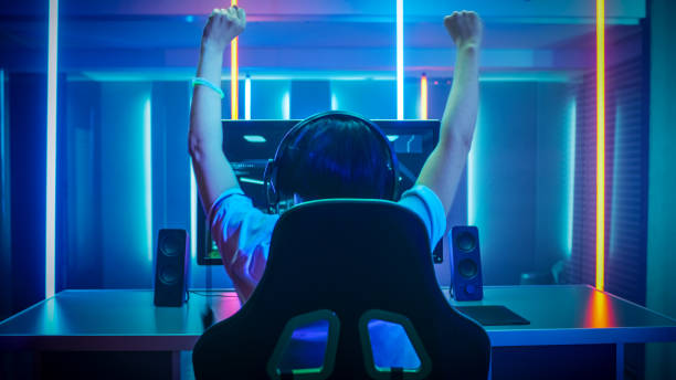 Professional Gamer Playing and Winning in First-Person Shooter Online Video Game on His Personal Computer. Footage Fade out into Bokeh. Room Lit by Neon Lights in Retro Arcade Style. Cyber Sport Championship. profesional jugador jugar y ganar en first-person shooter juego en línea de vídeo en su ordenador personal. material de archivo se descoloran hacia fuera en bokeh. sala iluminada por luces de neón en estilo retro arcade. campeonato de cyber deporte.