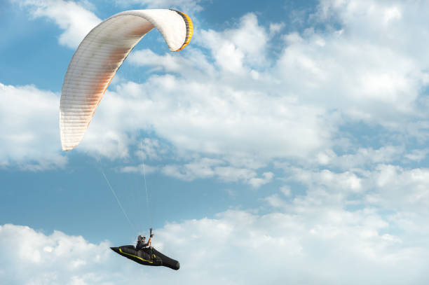 istock Professional paraglider flies on a white paraglider against the blue sky and white clouds. Paragliding sport 1010651038