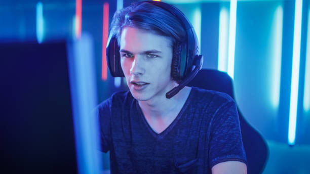 istock Young Pro Gamer Playing in Online Video Game, talks with Team Players through Microphone. Neon Colored Room. e-Sport Cyber Games Internet Championship. 1010651380