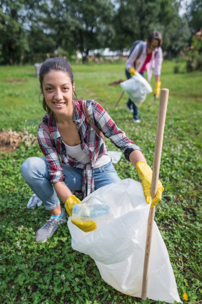 istock Young woman picking up plastic litter in the park 1010655450