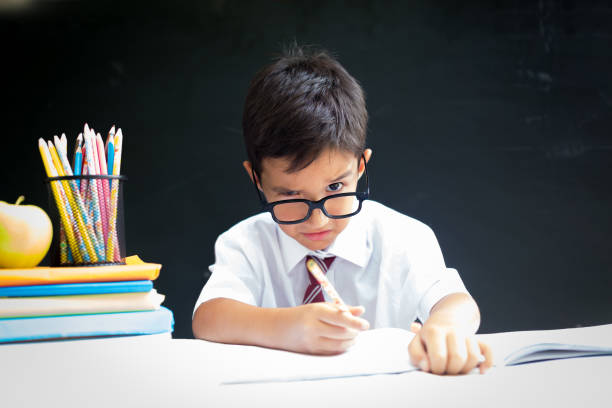 istock Cute handsome school boy in white shirt looking above the glasses, thinking over a problem 1010655970