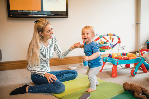 istock Mother Helping Her Baby Son Walk 1010659500