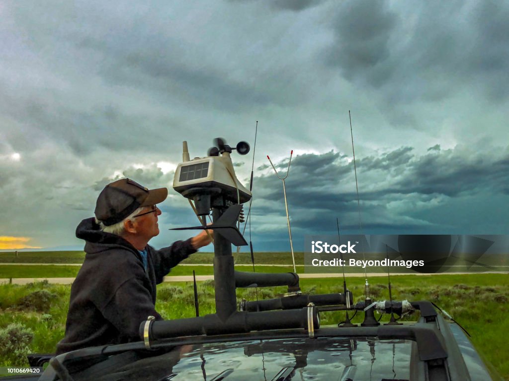 Storm-chaser adjusts the rooftop weather station on his chase vehicle as a severe storm builds in the background Legendary Aussie storm-chaser Clyve Herbert adjusts the rooftop weather station on his chase vehicle as a severe storm builds in the background Storm Chaser Stock Photo