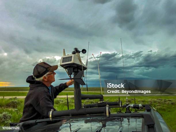 Stormchaser Adjusts The Rooftop Weather Station On His Chase Vehicle As A Severe Storm Builds In The Background Stock Photo - Download Image Now