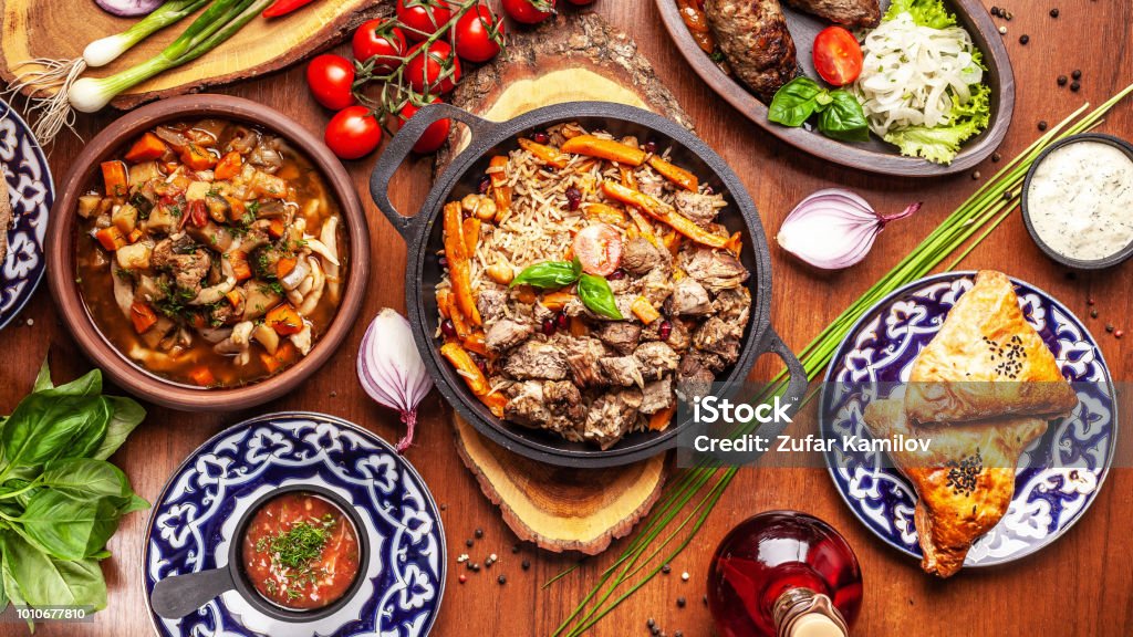 Traditional Uzbek oriental cuisine. Uzbek family table from different dishes for the New Year holiday. The background image is a top view. Food Stock Photo