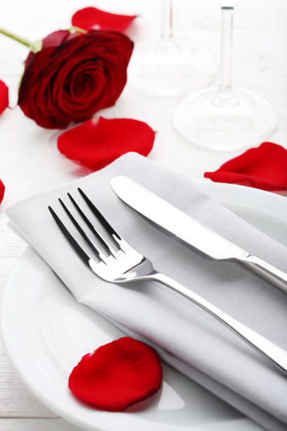 istock Kitchen cutlery in white plate with red rose petals on wooden table 1010681236