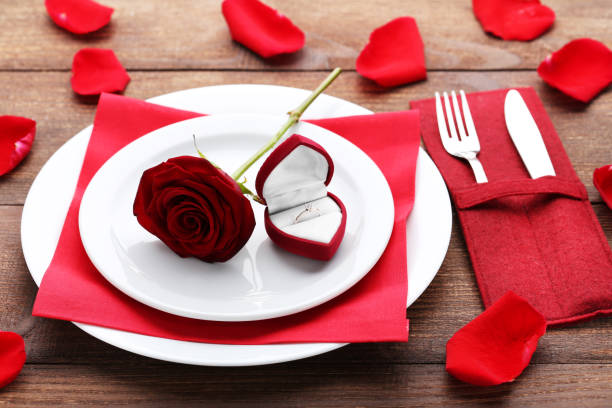 istock Silver ring with red rose on white plate and kitchen cutlery on wooden table 1010681442