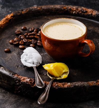 Bulletproof coffee with melted and coconut butter on dark background