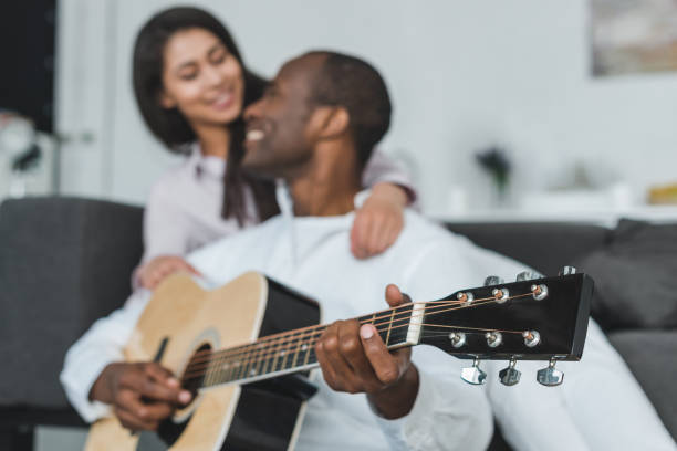istock african american boyfriend playing guitar for girlfriend at home with tuning keys on foreground 1010724708