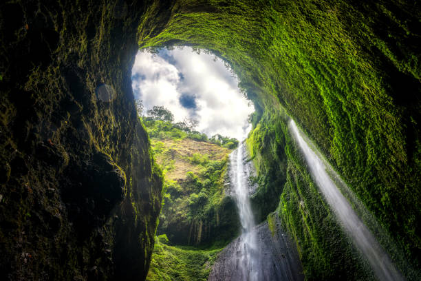 istock View of Madakaripura waterfall with green moss and blue sky in Java, Indonesia. 1010770744
