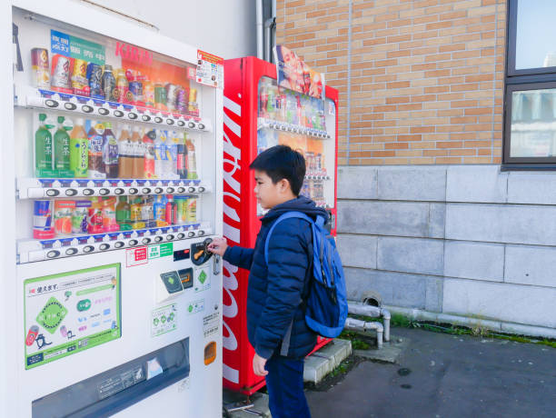 A boy selecting drink from automatic vending machine, at Otaru, Hokkaido, Japan. stock photo