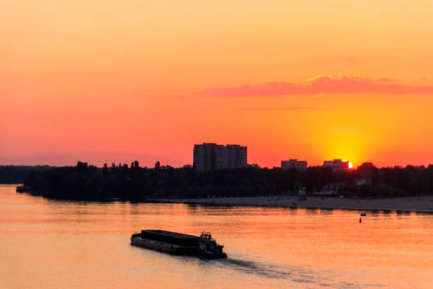 istock Tugboat pushing a heavy long barge on the river Dnieper at sunset 1010789022
