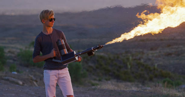 teenager shoots a flamethrower in a desert - flamethrower imagens e fotografias de stock