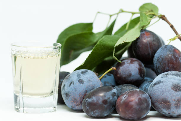 romanian plum brandy known as tuica or tzuica and heap of ripe plums on white - slivovitz imagens e fotografias de stock