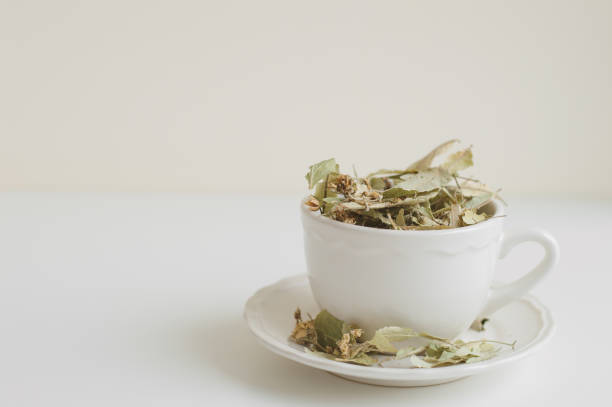 istock Lime flower tea in a white cup on white table. Dried herbal drink 1010831382