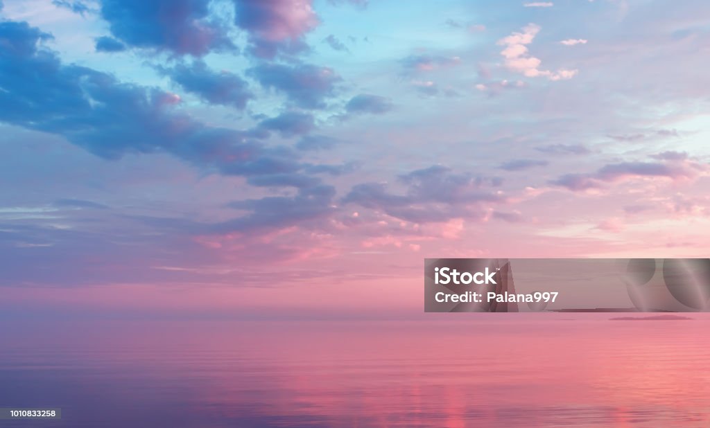 Misty Lilac Seascape With Pink Clouds Misty lilac seascape - pink and blue clouds over the water of calm Lake Onega and the small island in the White Nights season - Russia, Republic of Karelia. Soft focus. Sky Stock Photo