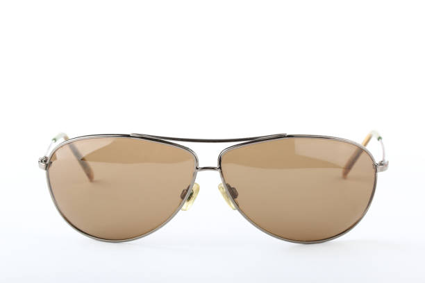 istock Single scratched old classic sunglasses with metal frame and brown lenses on a white background 1010835828