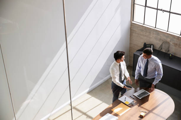 Two businessmen in discussion using laptop, elevated view Two businessmen in discussion using laptop, elevated view formal businesswear stock pictures, royalty-free photos & images