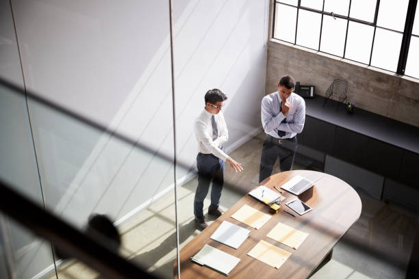 istock Two businessmen talk standing in an office, elevated view 1010835940
